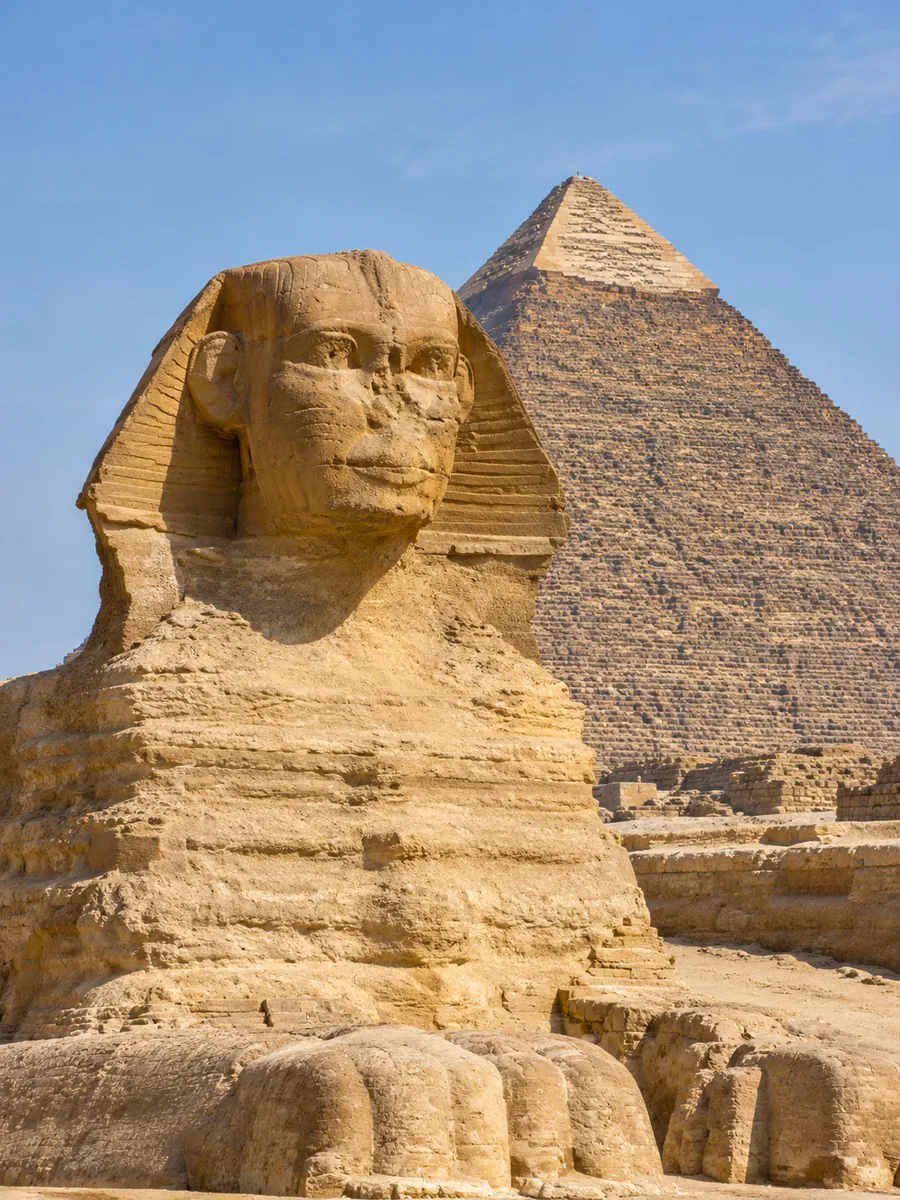 Der Kopf der Großen Sphinx mit der Chephren-Pyramide dahinter unter klarem Himmel